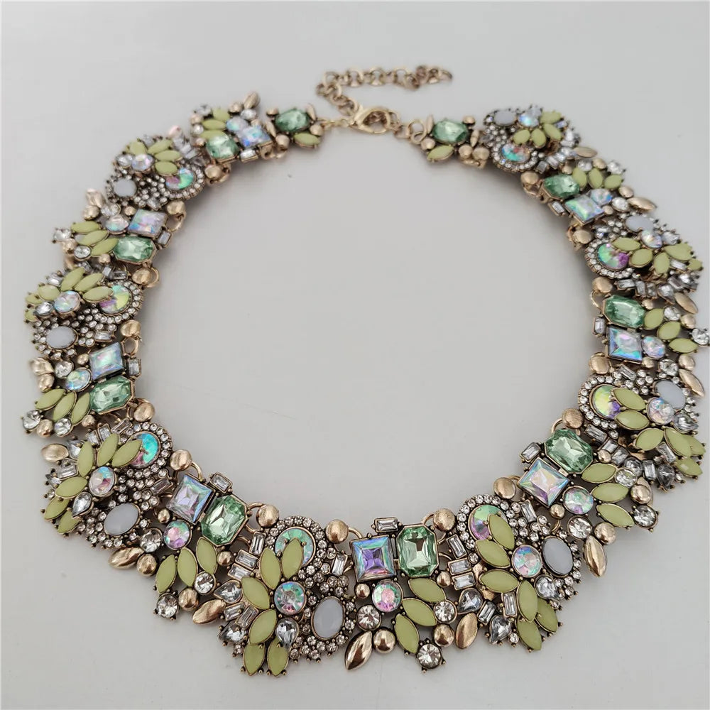 Decorative necklace with green and gold stones on a light gray background