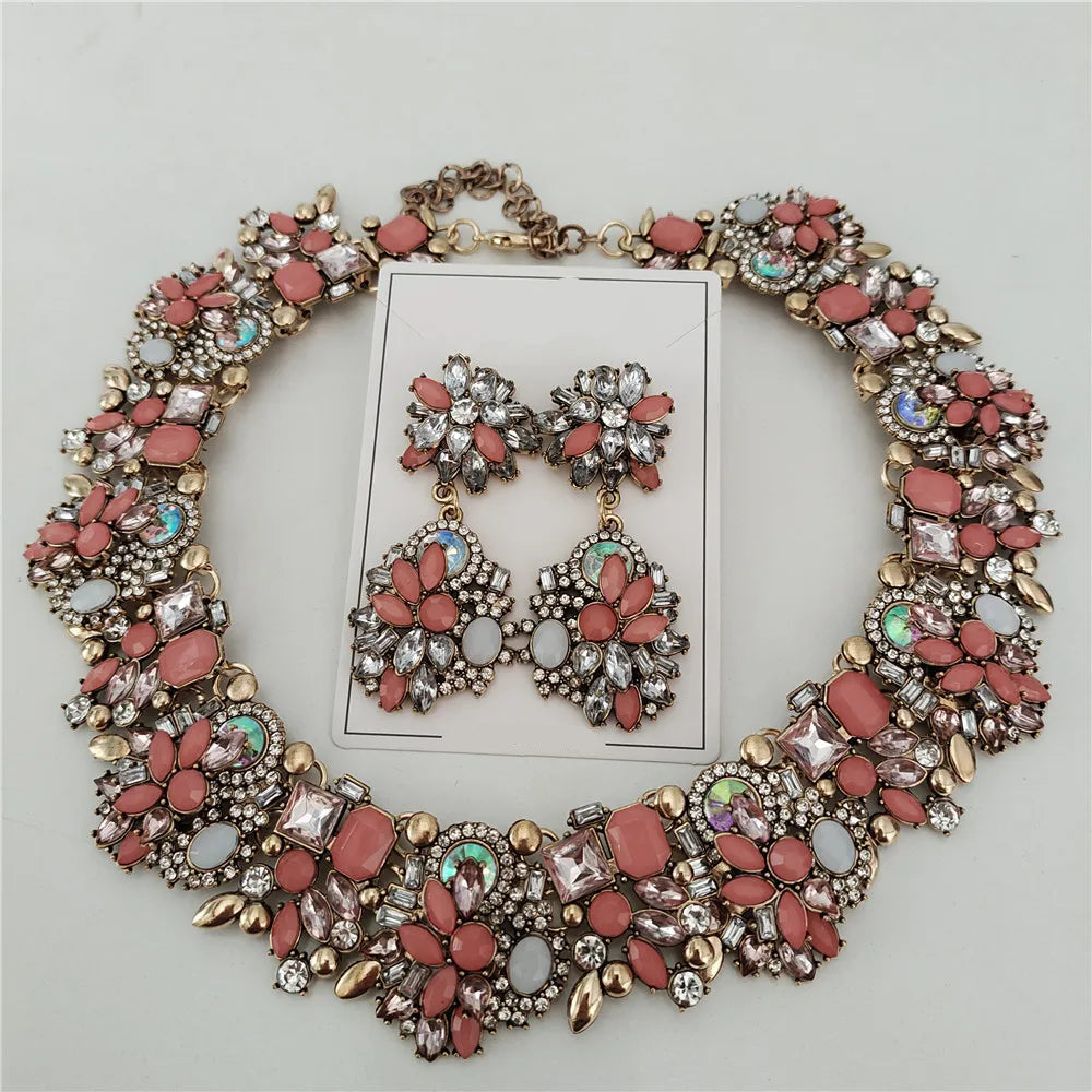 Necklace and earrings set with pink and gold details on a gray background