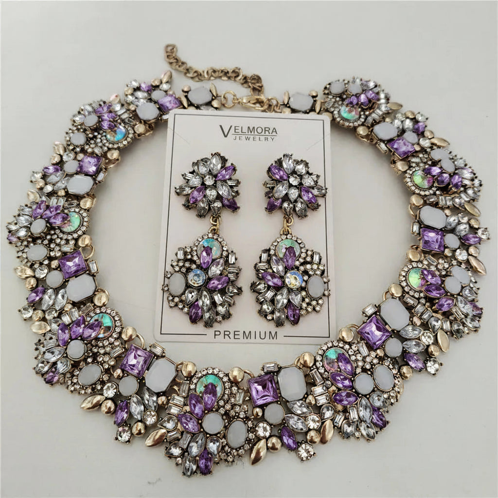 Purple and gold jewelry set with necklace and earrings on a gray background